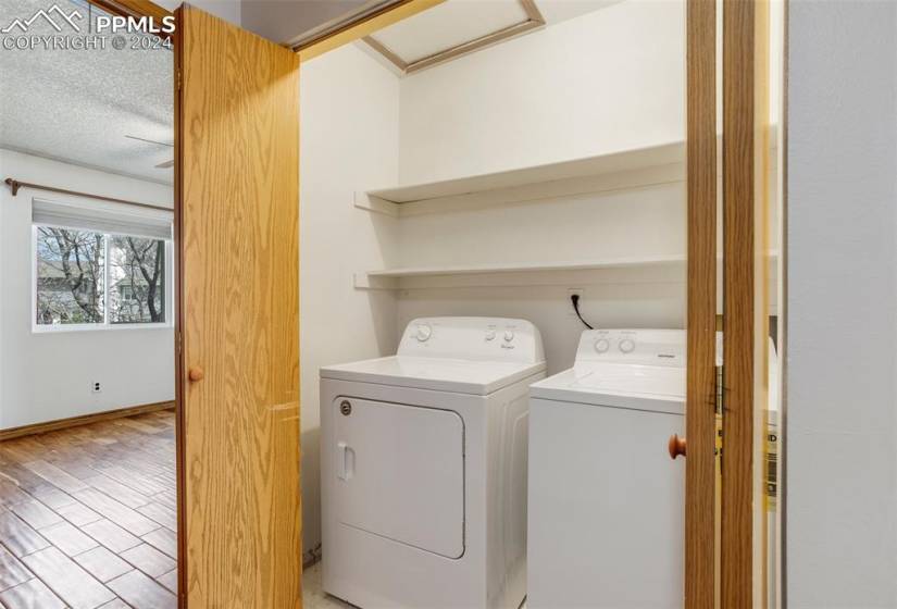 Washroom featuring independent washer and dryer, light hardwood / wood-style floors, and a textured ceiling