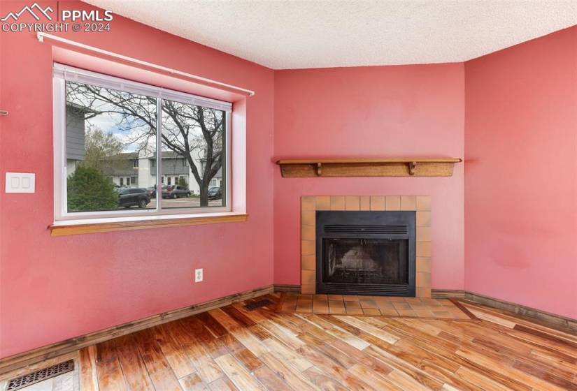 Unfurnished living room with wood-type flooring, a textured ceiling, a wealth of natural light, and a tile fireplace