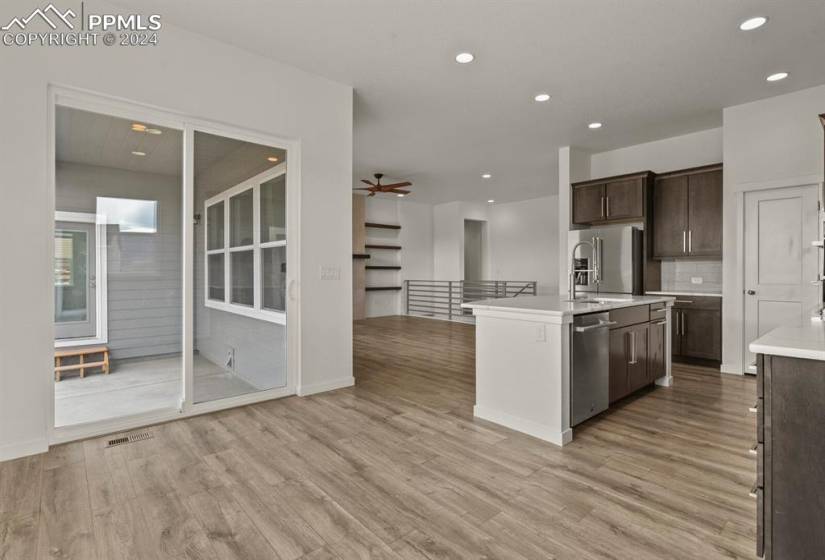 Kitchen featuring light wood-type flooring, appliances with stainless steel finishes, an island with sink, and a slider door leading to the backyard