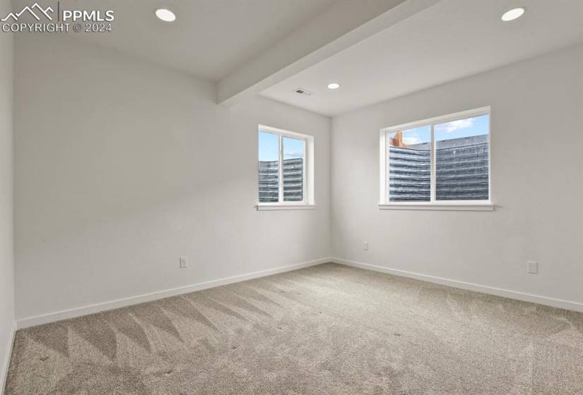 Carpeted bedroom in basement with beamed ceiling and plenty of natural light