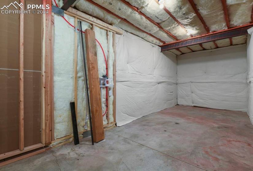 Unfinished storage room in basement with hookups for washer, dryer and a full refrigerator that is compatible for water/ice