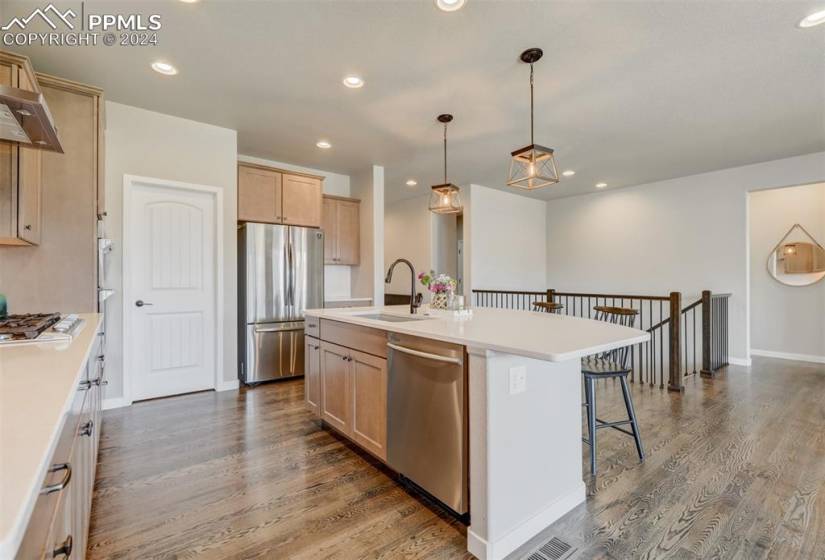 Kitchen with stainless steel appliances, hardwood / wood-style flooring, a kitchen island with sink, sink, and pendant lighting