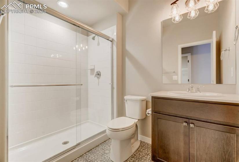 Bathroom featuring walk in shower, vanity, tile floors, and toilet