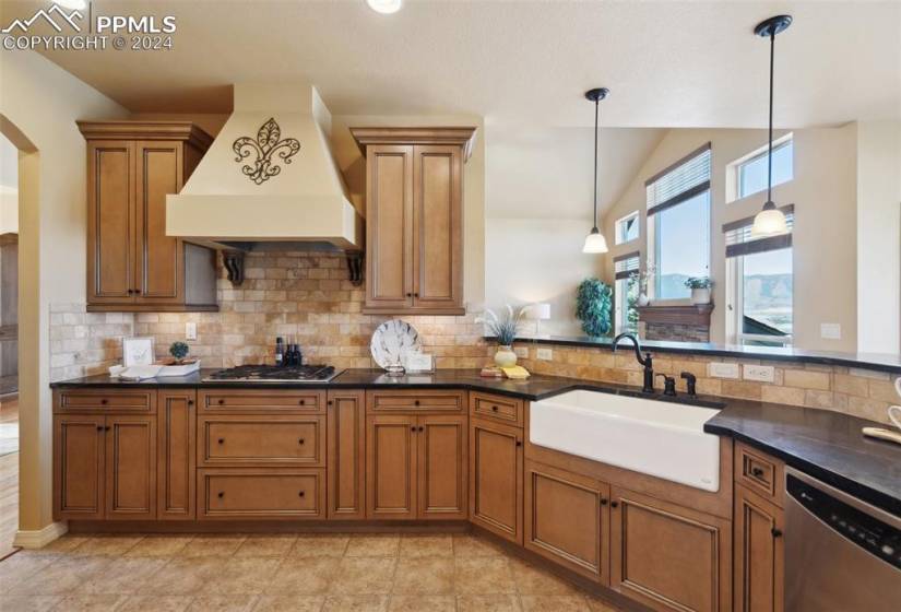 Kitchen with pendant lighting, premium range hood, stainless steel appliances, farmhouse sink, and tasteful tile backsplash