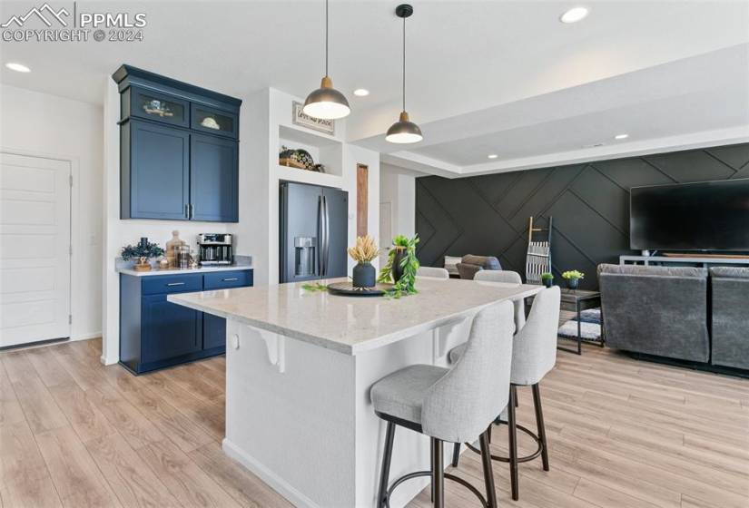 Kitchen featuring blue cabinetry, a kitchen island, light hardwood / wood-style floors, stainless steel fridge, and a breakfast bar