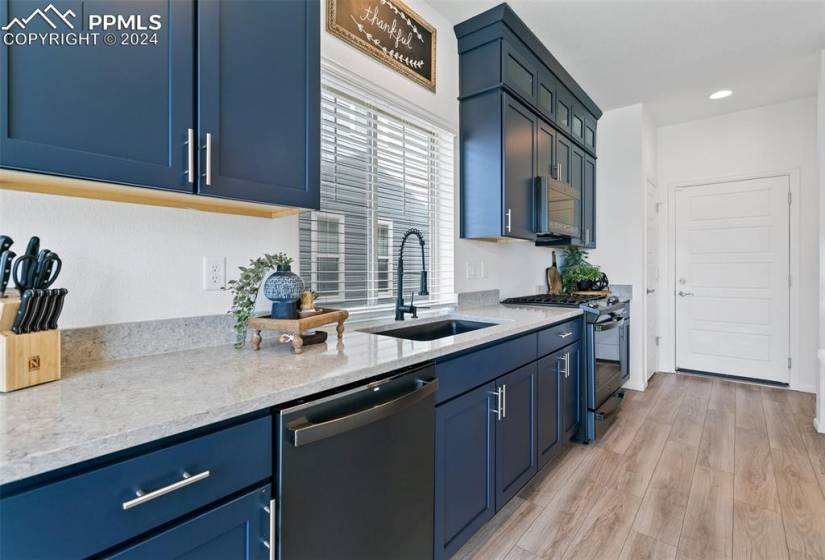 Kitchen with sink, stainless steel appliances, light wood-type flooring, and blue cabinetry