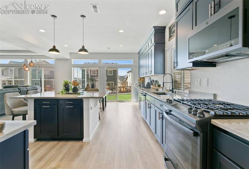 Kitchen featuring appliances with stainless steel finishes, a kitchen breakfast bar, sink, pendant lighting, and light wood-type flooring