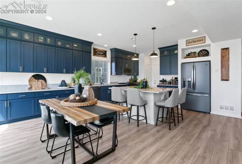 Kitchen with blue cabinets, light hardwood / wood-style floors, a center island, and stainless steel appliances