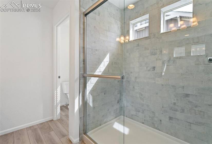 Bathroom featuring a shower with door, hardwood / wood-style flooring, and toilet