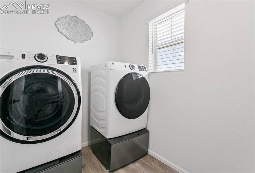 Laundry room with hardwood / wood-style flooring and washing machine and clothes dryer