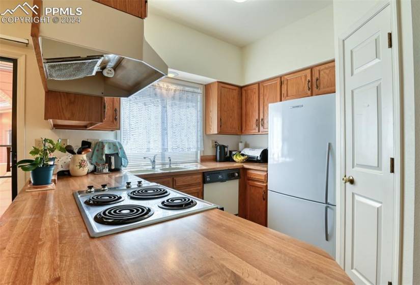 Kitchen with white appliances, light hardwood / wood-style floors, sink, and fume extractor