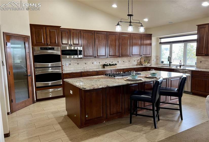 Kitchen with granite counters, appliances with stainless steel finishes, a center island, sink, and backsplash