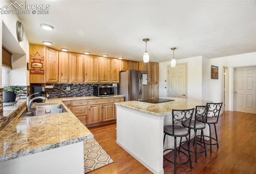 Kitchen featuring hanging light fixtures, appliances with stainless steel finishes, sink, a kitchen island, and light hardwood / wood-style floors all on the main level