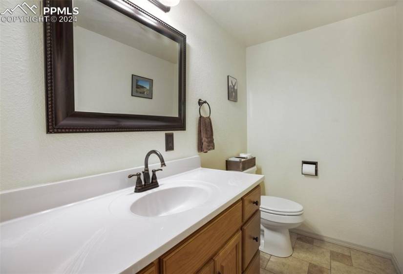 Bathroom featuring tile floors, vanity with cabinet space, and toilet on the main level close to the kitchen and bedroom