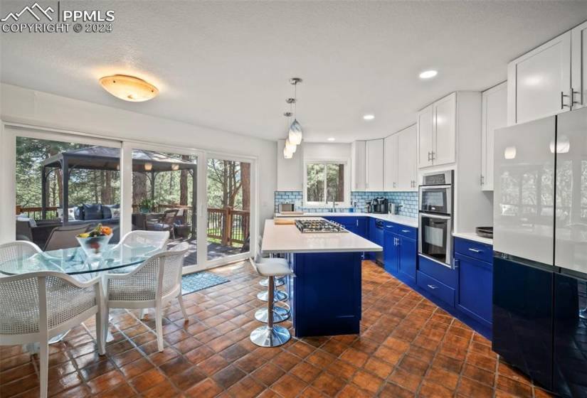 Kitchen featuring hanging light fixtures, dark tile flooring, blue cabinetry, and a breakfast bar
