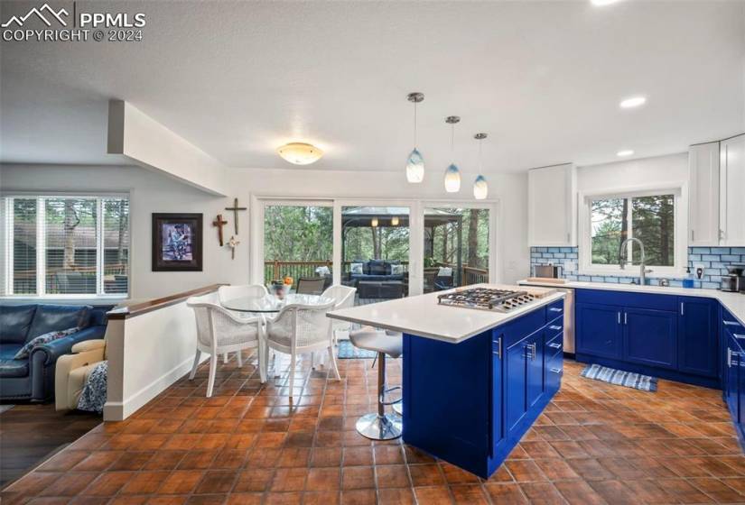 Kitchen featuring hanging light fixtures, a breakfast bar area, tasteful backsplash, white cabinets, and blue cabinets