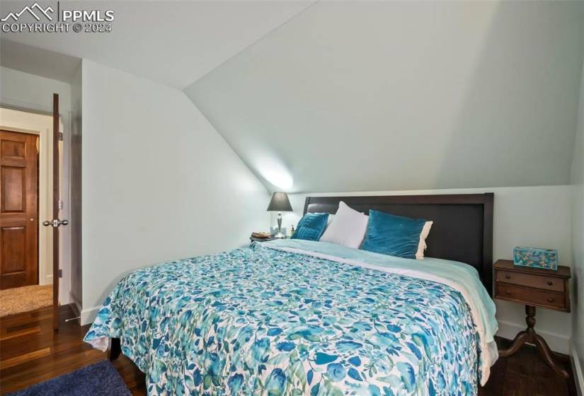 Bedroom featuring lofted ceiling and dark hardwood / wood-style flooring