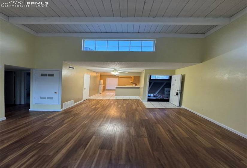 Unfurnished living room with hardwood / wood-style flooring, wood ceiling, ceiling fan, and beamed ceiling
