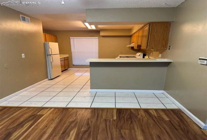 Kitchen featuring white refrigerator, light hardwood / wood-style floors, kitchen peninsula, and a textured ceiling