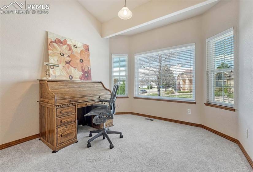 Main Level Office with neutral carpets and wall of windows with front yard views.