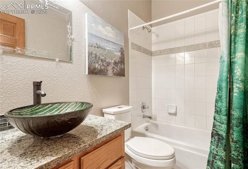 Remodeled Basement Full Bathroom with vanity, vessel sink, mirror, and tiled tub/shower.