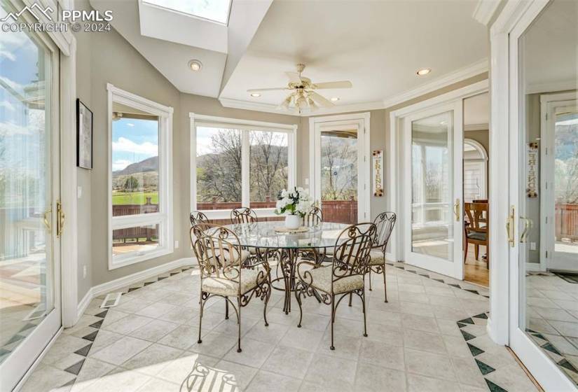 Sunroom / solarium with a skylight, plenty of natural light, and ceiling fan