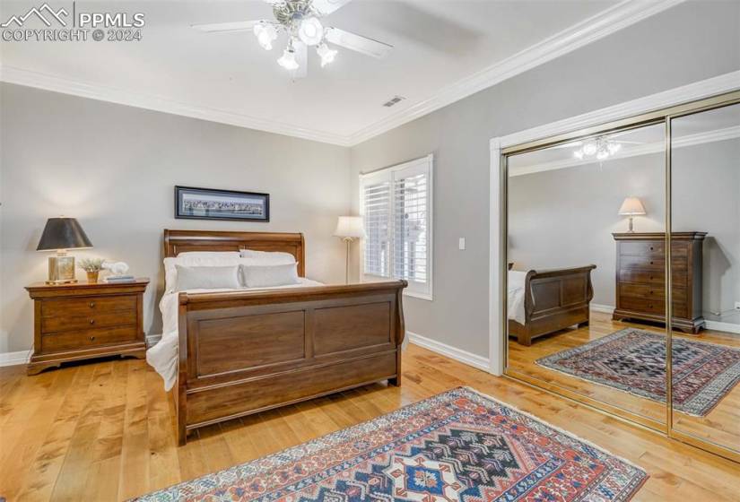 Bedroom with hardwood / wood-flooring, crown molding, ceiling fan, and a closet