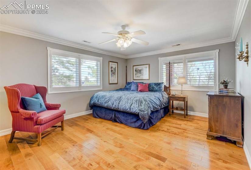 Bedroom with ceiling fan, light hardwood / wood-style floors, and crown molding