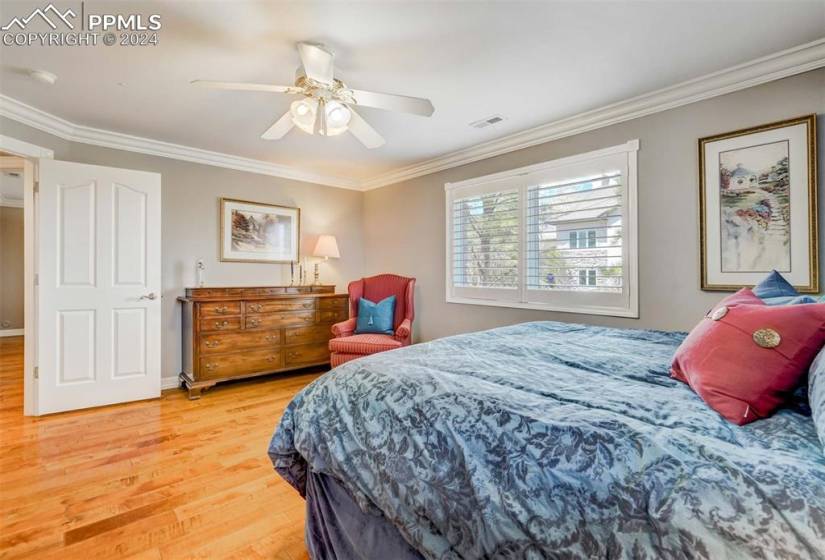Bedroom with hardwood / wood-style floors, ceiling fan, and crown molding