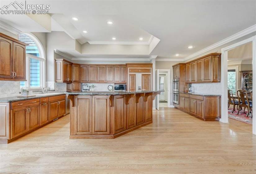 Kitchen featuring backsplash, a healthy amount of sunlight, light wood-flooring, and a kitchen island