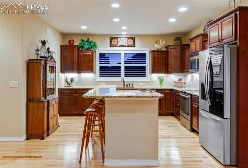 Kitchen featuring a center island, light hardwood / wood-style flooring, stainless steel appliances, a breakfast bar area, and backsplash