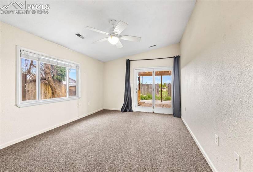 Carpeted empty room featuring ceiling fan and lofted ceiling