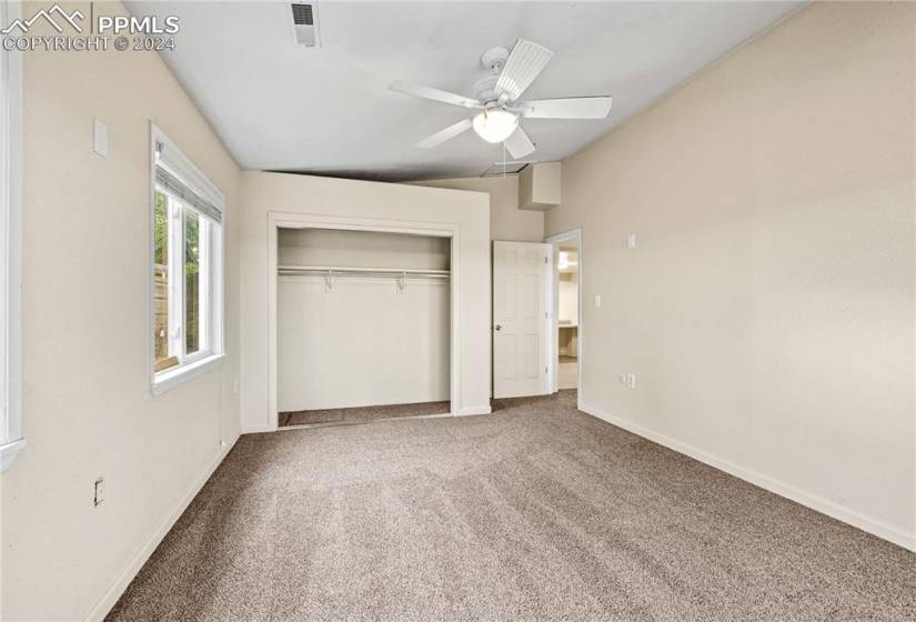 Unfurnished bedroom featuring a closet, ceiling fan, carpet floors, and vaulted ceiling