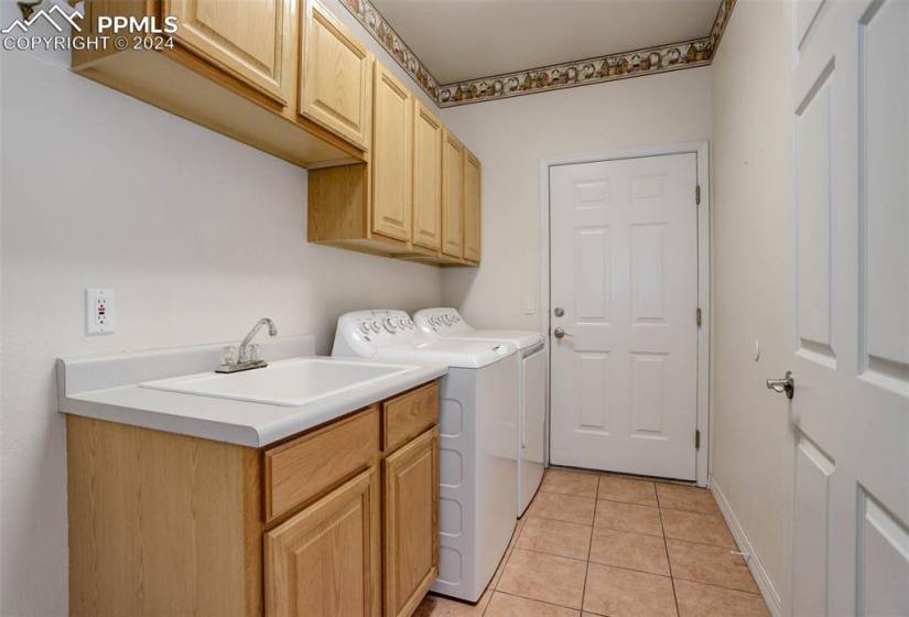 Main level laundry featuring sink, light tile flooring, independent washer and dryer, and cabinets