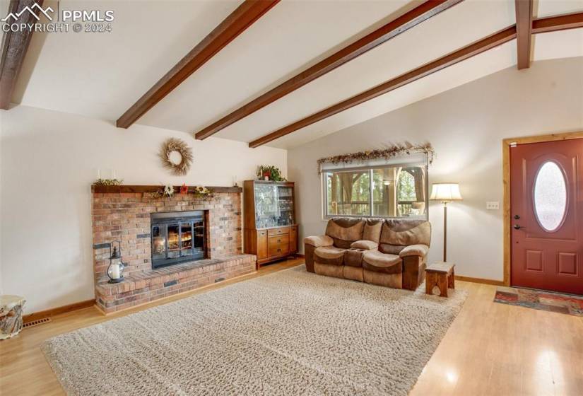 Living room featuring lofted ceiling with beams, a fireplace, and wood-type flooring