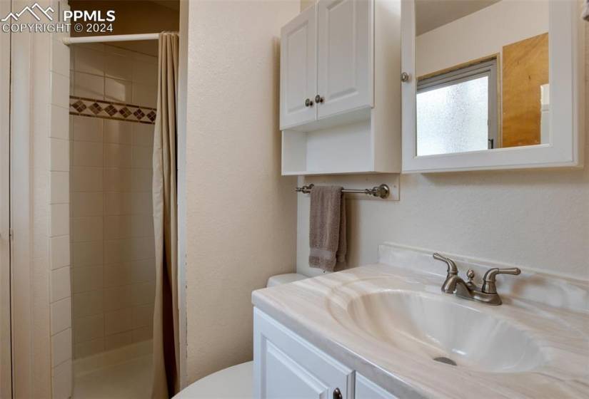 Bathroom featuring a shower with curtain, oversized vanity, and toilet