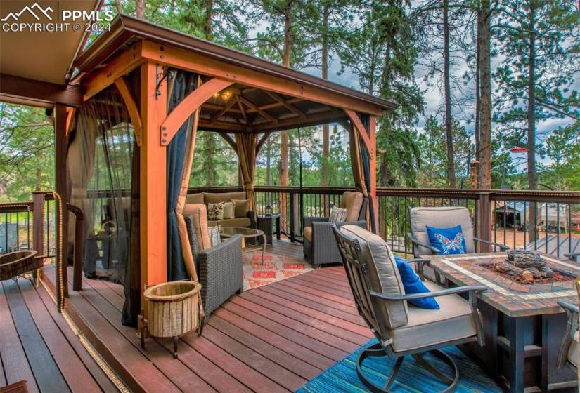 Wooden terrace featuring an outdoor living space with a fire pit and a gazebo