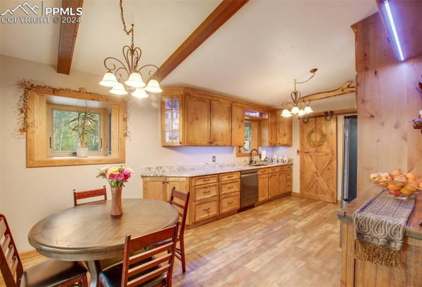 Kitchen featuring beamed ceiling, light hardwood / wood-style floors, hanging light fixtures, and an inviting chandelier