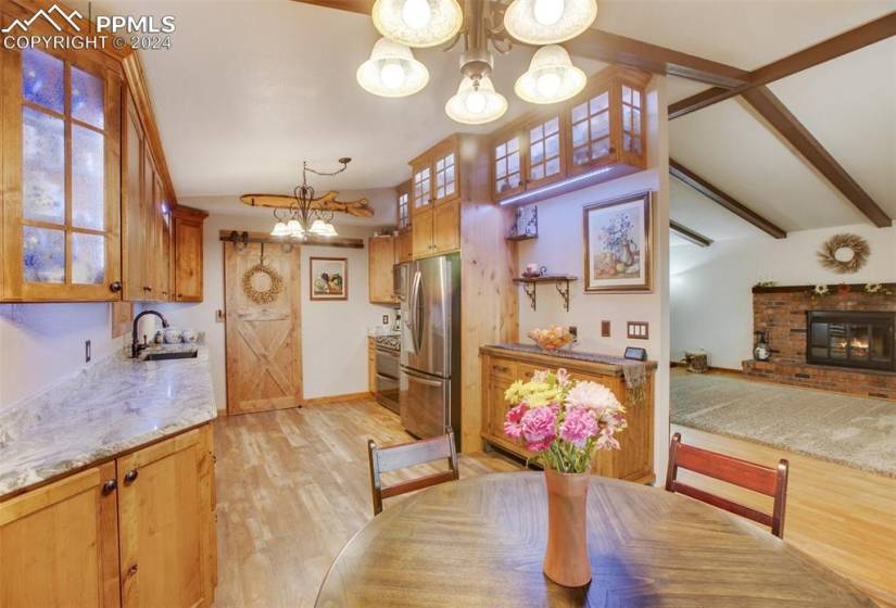 Dining space featuring a wealth of natural light, a fireplace, light wood-type flooring, an inviting chandelier, and sink