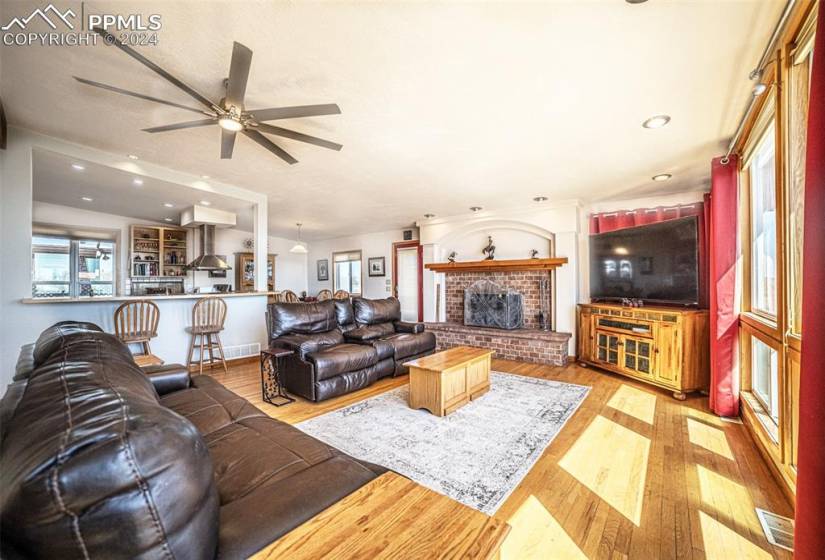 Living room featuring a brick fireplace, ceiling fan, and light hardwood / wood-style flooring