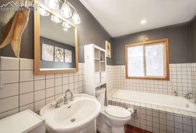 Bathroom with sink, a relaxing tiled bath, tile walls, and tile flooring