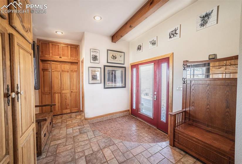 Mudroom featuring beam ceiling and light tile floors