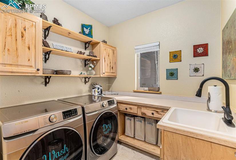 Laundry room with cabinets, sink, light tile floors, and washing machine and dryer