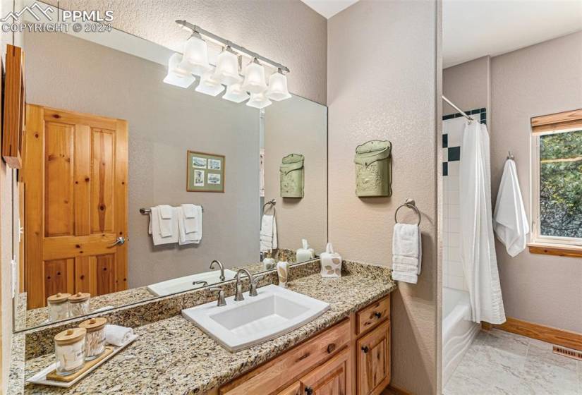 Bathroom featuring tile flooring, shower / bath combination with curtain, a textured ceiling, and vanity