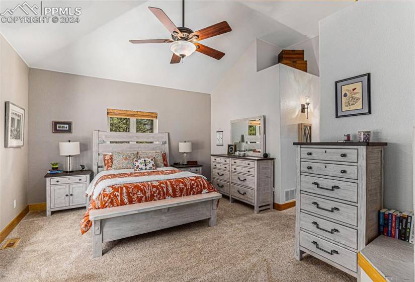 Bedroom with high vaulted ceiling, ceiling fan, and light carpet