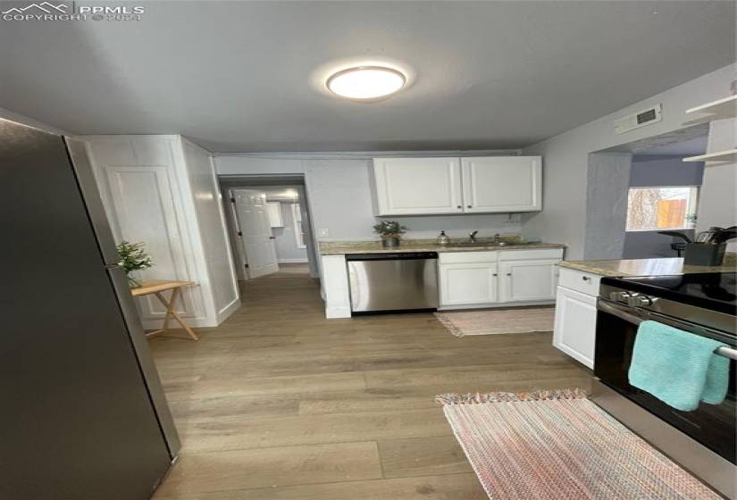 Kitchen featuring stove, dishwasher, white cabinetry, and light hardwood / wood-style flooring