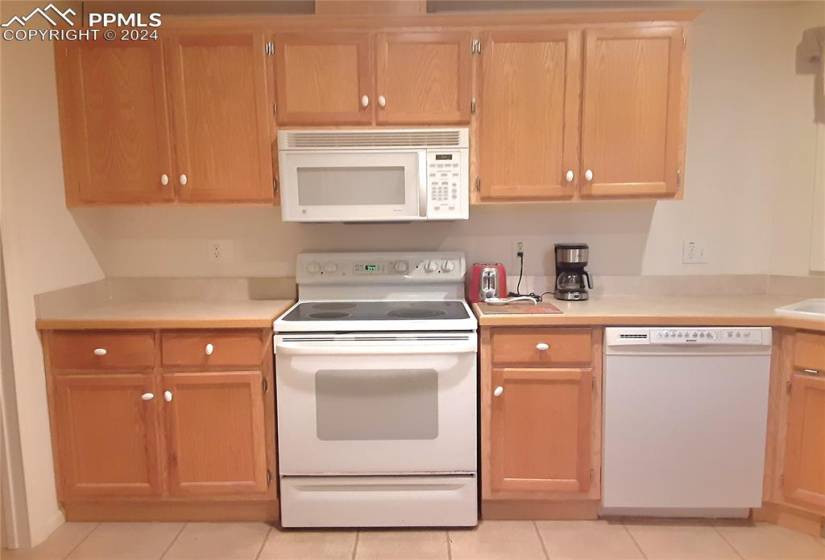 Kitchen featuring white appliances and light tile flooring