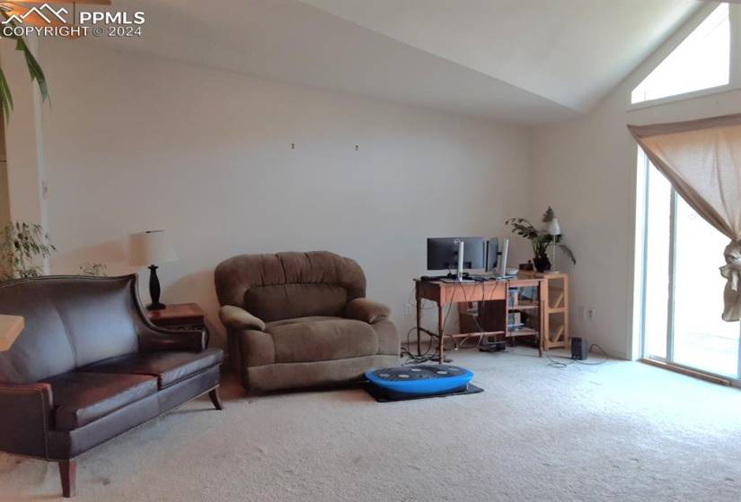 Living room featuring carpet flooring, lofted ceiling, and ceiling fan