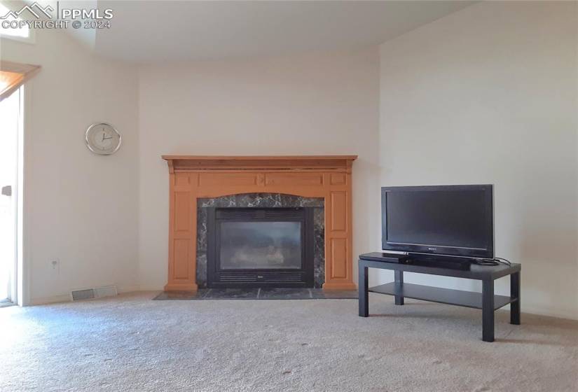 Living room featuring vaulted ceiling, carpet, and a high end fireplace