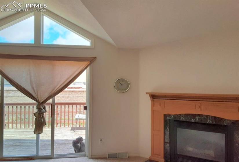 Living room with lofted ceiling, carpet floors, a fireplace, and a wealth of natural light